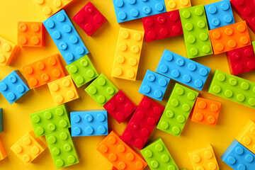 Obraz premium Constructor toy. Many colorful building blocks on yellow background, flat lay