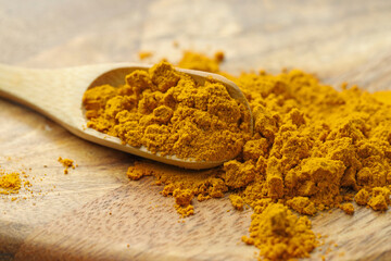 Turmeric powder and spoon on table, closeup