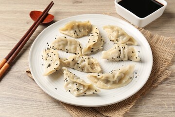 Delicious gyoza dumplings with sesame seeds served on wooden table, closeup