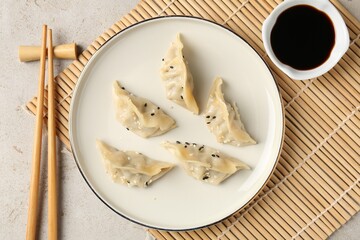 Delicious gyoza dumplings with sesame seeds served on light table, top view