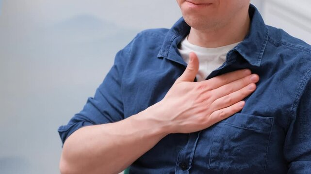 The man coughs and rubs his chest, the concept of a sick heart and pneumonia, burning of the chest.