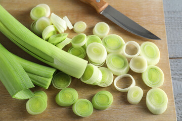 Fresh chopped leeks and knife on wooden table, closeup