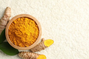 Turmeric powder in bowl, roots and leaves on light textured table, flat lay. Space for text
