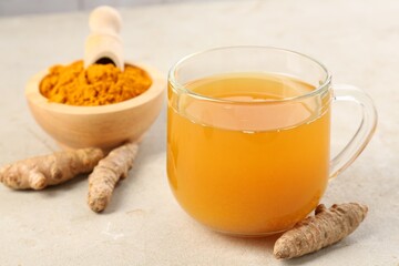 Aromatic turmeric tea, rhizomes and powder on white textured table, closeup