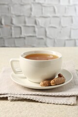 Aromatic turmeric tea and rhizomes on white textured table. Space for text