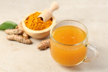 Aromatic turmeric tea, rhizomes and powder on white textured table, closeup