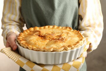 Woman with homemade pie on blurred grey background, closeup