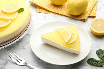 Piece of tasty lemon cheesecake, fork, mint and citrus fruits on white marble table, closeup