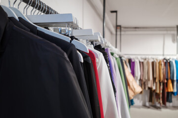 Obraz premium A close-up view of a clothing rack in a boutique, featuring a selection of garments in various colors, including black, red, white, and purple.