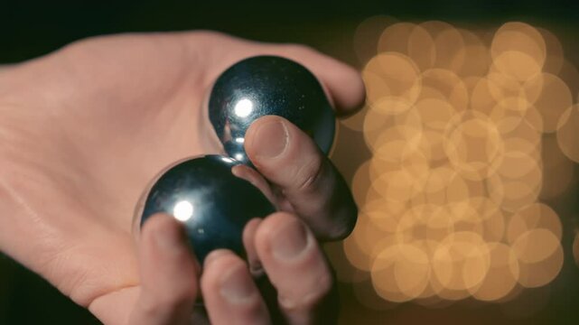 Hand rolling Baoding Balls, close-up shot, golden bokeh lights, meditative mood