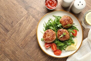 Delicious patties with greens, tomatoes, ketchup and drink on wooden table, flat lay. Space for text