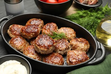Delicious patties in baking dish and spices on table, closeup