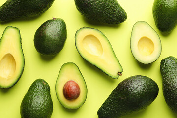 Whole and cut avocados on light green background, flat lay
