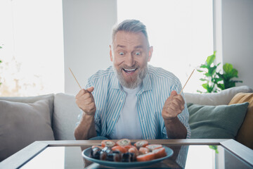 Elderly man enjoying sushi at home, expressing happiness and excitement during a relaxed weekend