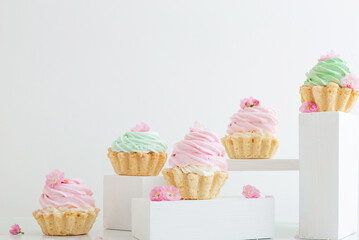 pink and green cupcakes with spring flowers  on wooden podiums on white  background