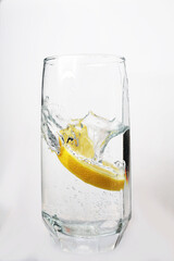 a slice of lemon falls into a glass of soda, with water