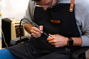 Instrument repairman using rotary tool in workshop