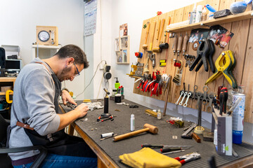 Instrument repairman working on wind instrument in workshop