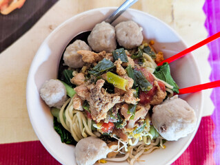The top appearance of chicken noodles with meatballs in one bowl on the table.