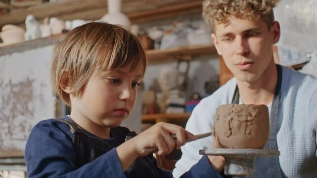 Boy in pottery studio, wheel spinning, hands shaping clay into traditional art, his craft bridging hobby and handmade heritage.