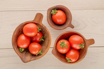 Ripe cocktail tomatoes in wooden cups, on a wooden table, close-up, top view.