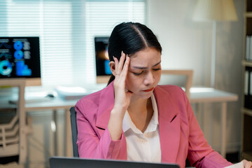 Asian business woman suffering from headache, migraine or stress while working on laptop computer...