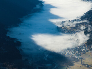 Aerial drone view of sunny winter in dolomites, alps.Pinzolo village and a ski resort in Italy. Dolomites Brenta, town in the Dolomites covered in fog, view from a drone.