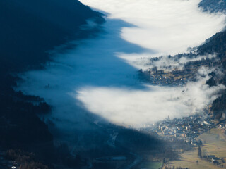 Aerial drone view of sunny winter in dolomites, alps.Pinzolo village and a ski resort in Italy. Dolomites Brenta, town in the Dolomites covered in fog, view from a drone.
