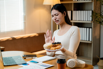 Slim female turning away from junk food, selecting nutritious meal while maintaining weight loss goals