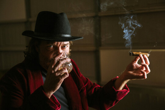 man smoking cigar and drinking whiskey