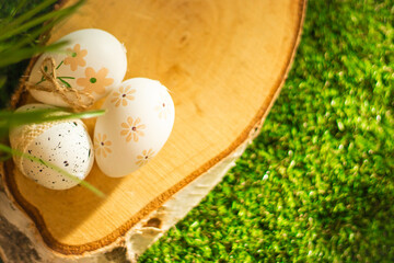 Easter eggs on a birch log slice, with natural wood and green grass, perfect for nature-inspired Easter decorations
