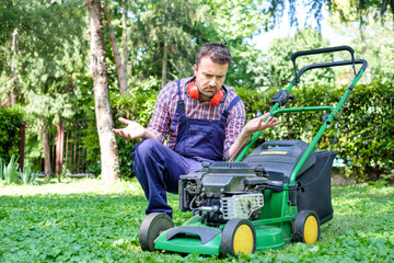 One guy portrait cutting the garden grass having problem with the lawn mower