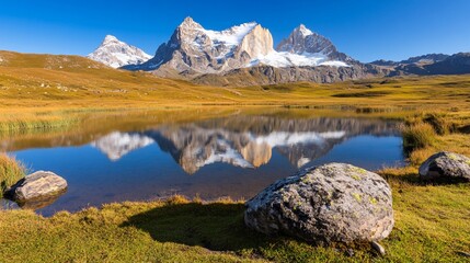 Fototapeta premium Majestic Snowcapped Mountains Reflected in Calm Blue Lake Golden Grassland