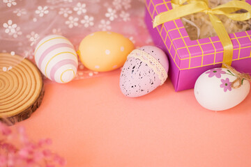 An Easter composition with colorful Easter eggs, dried flowers, a natural wood slice, and gift packaging on a soft pink background, perfect for Easter sales, promotions, and holiday discounts