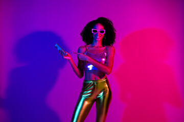 Naklejka premium Stylish woman illuminated by neon lights in vibrant club atmosphere, wearing retro-inspired outfit and glowing with joyful confidence.