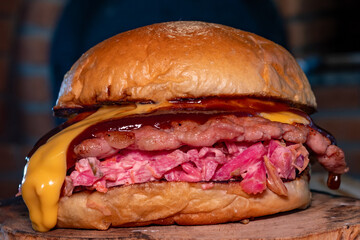 Brioche Bun Sandwich Filled with Smash Pork Meat with Pink Salad, Cheese and Barbecue Sauce on a Wooden Surface.