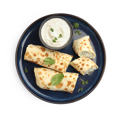Delicious crepes with cottage cheese, spinach and sour cream isolated on white, top view