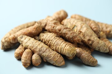 Pile of tumeric rhizomes on light blue background, closeup