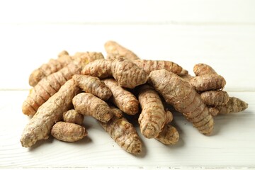 Pile of tumeric rhizomes on white wooden table, closeup