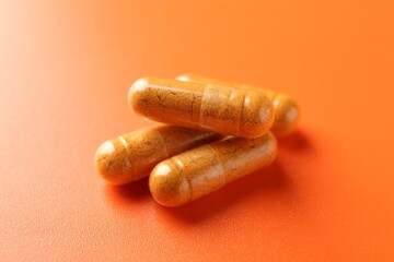 Many turmeric capsules on orange background, closeup