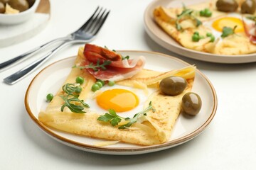 Delicious crepes with eggs and bacon served on white table, closeup