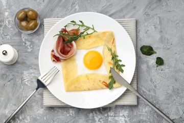 Delicious crepe bretonne with bacon and arugula served on grey textured table, flat lay