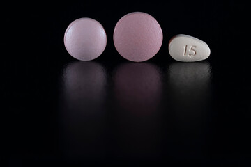 Three colored pills isolated on black with reflection