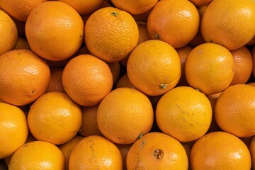A close-up view of a vibrant pile of fresh oranges, showcasing their glossy texture and bright...