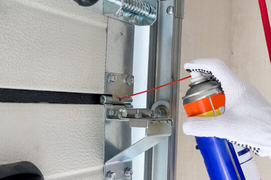 A worker lubricates sectional doors after installation in a garage.