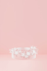 3D realistic podium background - frosted transparent glass cylindrical pedestal on pink. Glass spring flowers wreath as decor, mockup, 3d rendering. Stage for placement product, showcase platform.