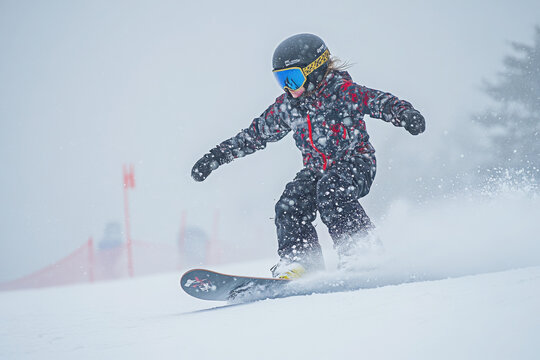 Young snowboarder in action on a snowy slope, wearing protective gear and a red-patterned jacket, capturing the thrill of winter sports and exhilaration of snowboarding. - Powered by Adobe