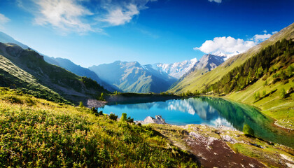 Scenic Mountain Lake: A serene alpine lake reflects the clear blue sky and surrounding majestic mountains, painting a picture of tranquility and natural beauty.