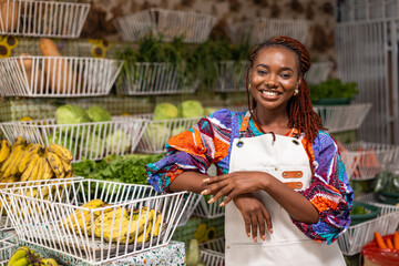 Smiling African woman, successful small business owner of a grocery shop selling fresh healthy fruits and vegetables produce.