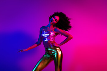 Naklejka premium A stylish young woman enjoying herself in vibrant neon lights with colorful fashion, expressing happiness and charm
